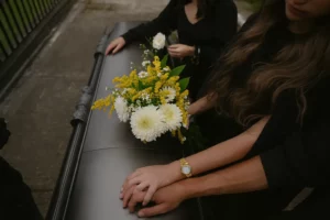 Mains endeuillées posées sur un cercueil lors d'une cérémonie funéraire.